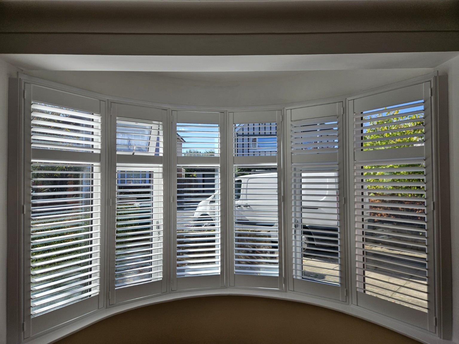 Andrew’s white plantation shutter installation in a curved bay window